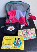 Front view showing Mickey Magic Kingdom backpack with three small Disney accessories