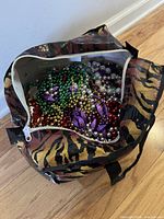 Tiger-print tote bag opened showing large quantity of multicolour bead necklaces