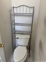 Front view of assembled silver metal over-toilet shelf with three tiers