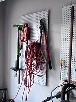 Pegboard with hedge trimmer, lopper, extension cord, manual edger