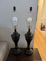 pair of black metal table lamps on table with bulbs and harps
