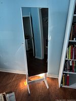 Full view of closed armoire showing white frame and full-length mirror