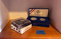 Coin set and pin set in their presentation boxes