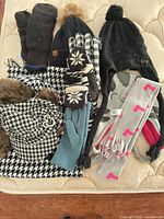 Various winter hats, gloves and scarves laid out on mattress