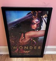 Framed Wonder Woman poster standing against wall showing full image and frame