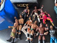 Group of loose WWE figures on table beside corner of NXT ring