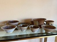Group shot of all eight signed iridescent stoneware pieces on shelf