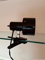 Side view of clamp lamp showing cylindrical shade, swivel bracket, clamp and cord