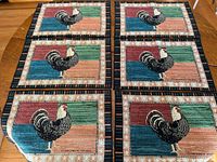 Six identical Warren Kimble rooster woven placemats laid flat