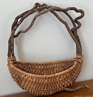 Front view of woven wicker basket suspended within twisted vine frame