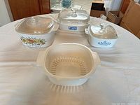 All three casserole dishes with lids and plastic colander displayed