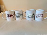 Set of four mugs side by side showing both green and maroon print variants