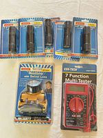 Group shot showing four packaged mini flashlights, one packaged headlamp, one packaged multimeter
