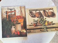 Both framed prints displayed together on table showing relative size and imagery