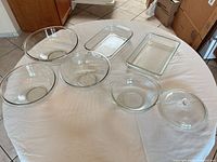 All seven Pyrex pieces laid out on table: four bowls, two baking dishes, one lid