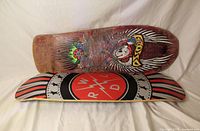 Two skateboard decks stacked to show graphics and wear