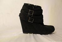 Right side profile of black wedge ankle boot showing buckles and heel