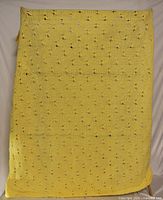 Full view of yellow hand-knitted blanket displaying size and openwork pattern