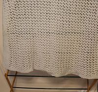 Full view of hand-knitted white blanket draped to show pattern and edge
