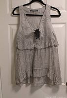 Front view of grey-white striped sleeveless Animale blouse on hanger