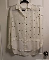 Front view of Alfred Sung ivory blouse with black rectangular print hanging on hanger