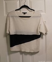 Front view of ivory mesh blouse with black diagonal panel on hanger