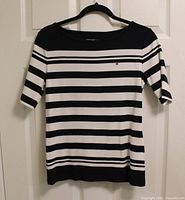 Front view of black and white striped Tommy Hilfiger blouse on hanger