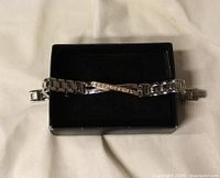 Top view of silver-tone link bracelet with angled gold-tone accent in black box