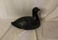 side profile of black soapstone loon carving on white backdrop