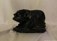 Side profile of carved black bear holding fish on small base