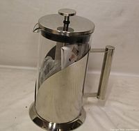 Full view of Cafe Du Chateau stainless steel and glass French press with plunger and leaflet inside