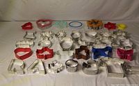 All 34 metal and plastic cookie cutters laid out showing assorted shapes and colors