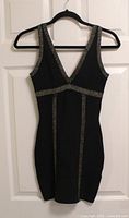 Front view of black bandage dress with silver trim on hanger