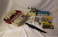 Overall view showing Shimano reel with box, rod rack box, filleting knife, tackle box and assorted lures