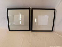 Front view of two identical black square frames with white mats