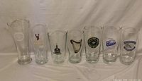 Front view of seven branded draft pint glasses aligned side by side