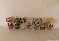 Front view of seven printed glass tumblers lined up