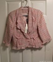 Front view of Scapa pink tweed jacket showing ruffle trim, bows, size tag attached