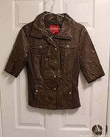 Full front view of brown Guess jacket hanging on door