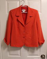 Front view of orange Tanjay blazer hanging to show style, color, buttons and lapels