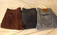 Three folded jeans showing back pockets and colors