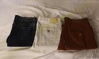 Three folded jeans, showing back pockets and colours
