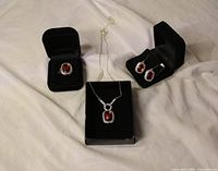 Complete jewelry set displayed in black boxes showing ring, necklace, and earrings