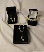 Full view of necklace, bracelet, and earrings displayed on black holders