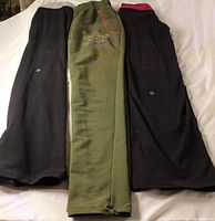 Front view of three pairs of leggings showing colors, logos and waistband details