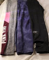 Three pairs of leggings laid flat showing colours, logos and overall condition