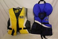Shows both Fluid life jackets front view highlighting colors, straps, logos, and relative sizes.