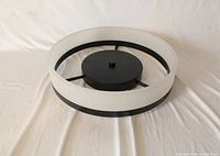 Top view of round LED ceiling light showing black center disk, three radial supports, white diffuser ring