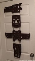 Entire metal totem wall hanging displayed on door showing overall design and linked panels