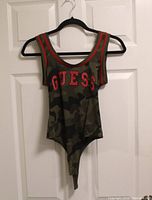 Front view of Guess camouflage bodysuit hanging on hanger